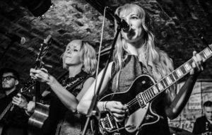 MonaLisa Twins at the Cavern Club 2014, black and white picture with Mona and Lisa in the foreground, on guitars and vocals