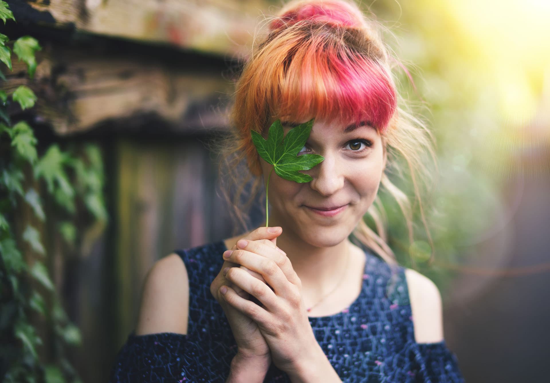 Colorful portrait of Lisa hiding one eye behind an ivy leaf